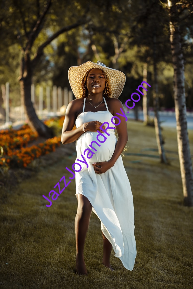 woman in white spaghetti strap dress wearing brown sun hat standing on green grass field during